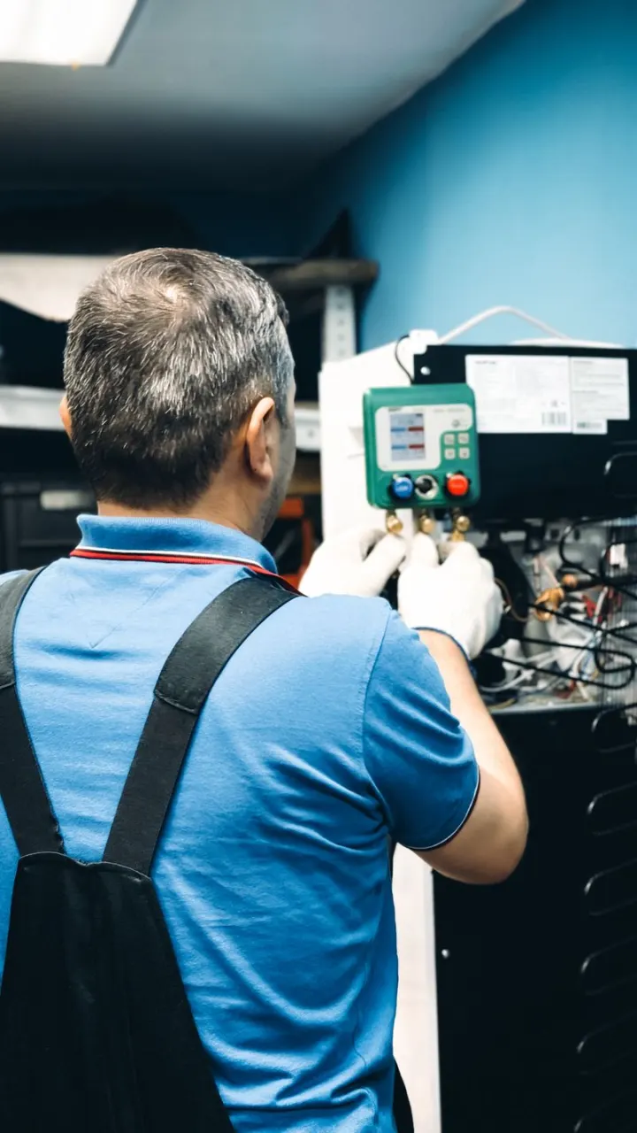 A technician reading digital gauges at an AC unit