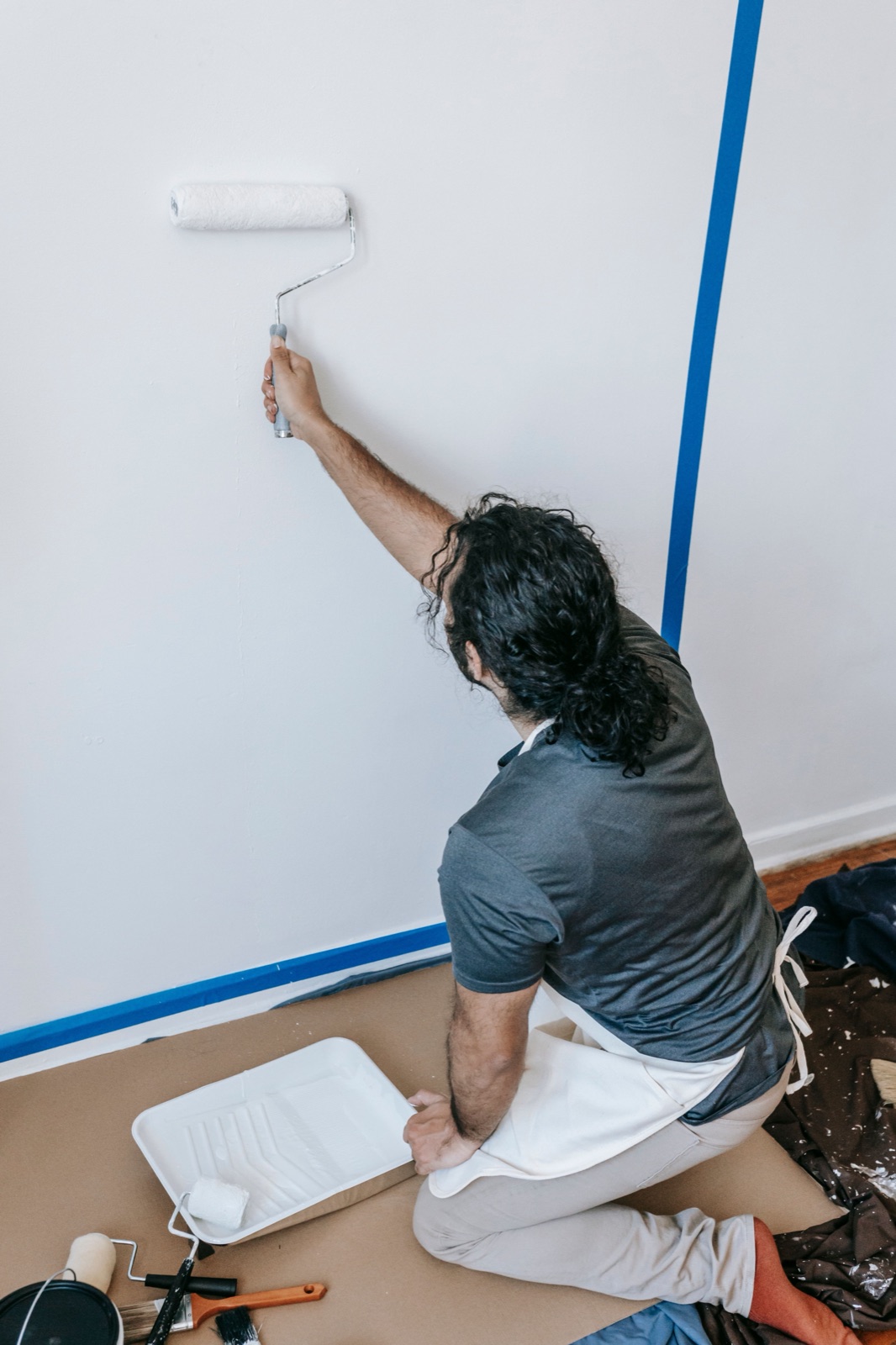 Rolling the first coat onto a taped wall, drop cloth down