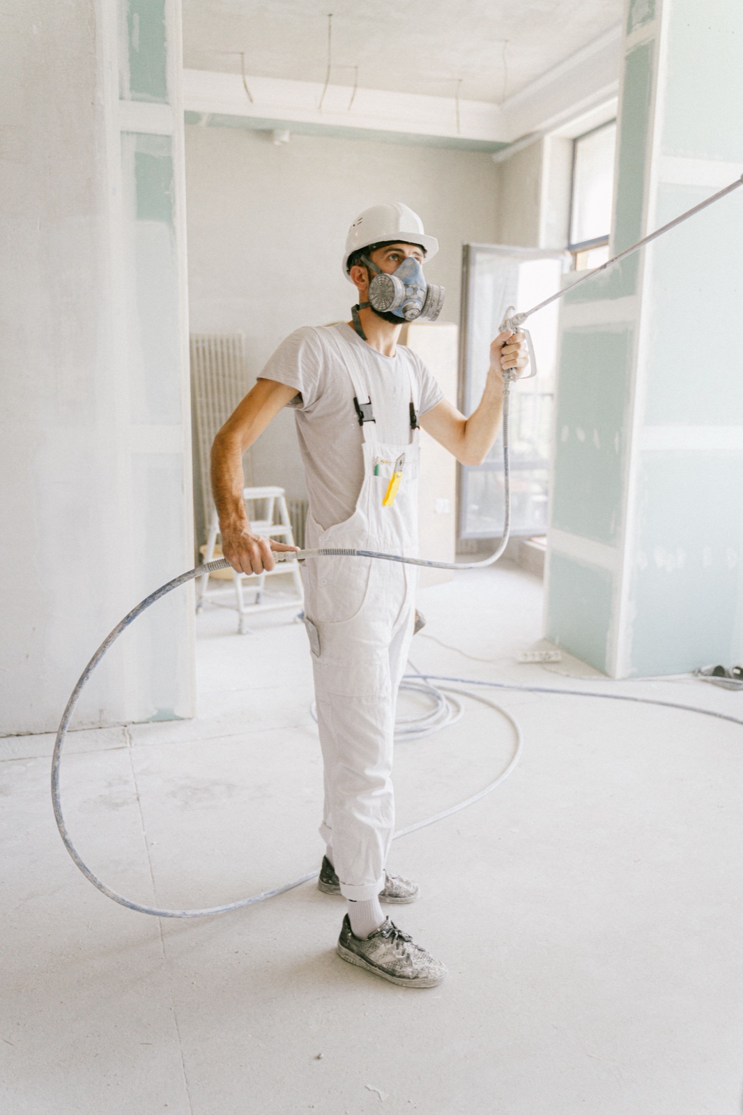 Andre, respirator on, spraying cabinet doors in the shop